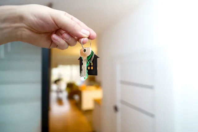 Main tenant les clés d'un logement, l'appartement en arrière-plan